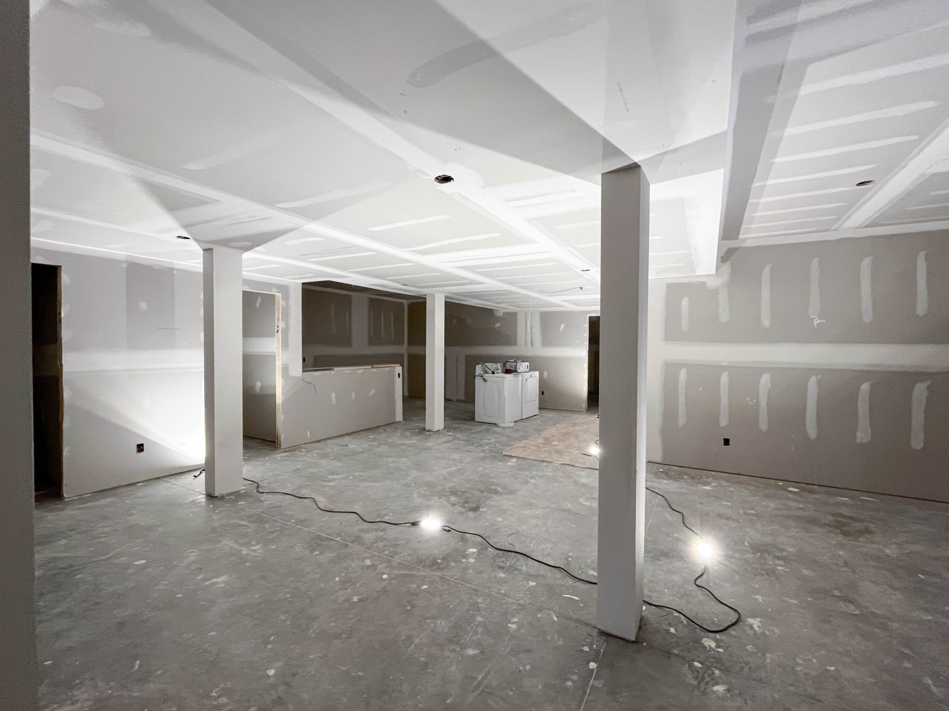 Interior of a home under restoration with freshly taped drywall and work lighting