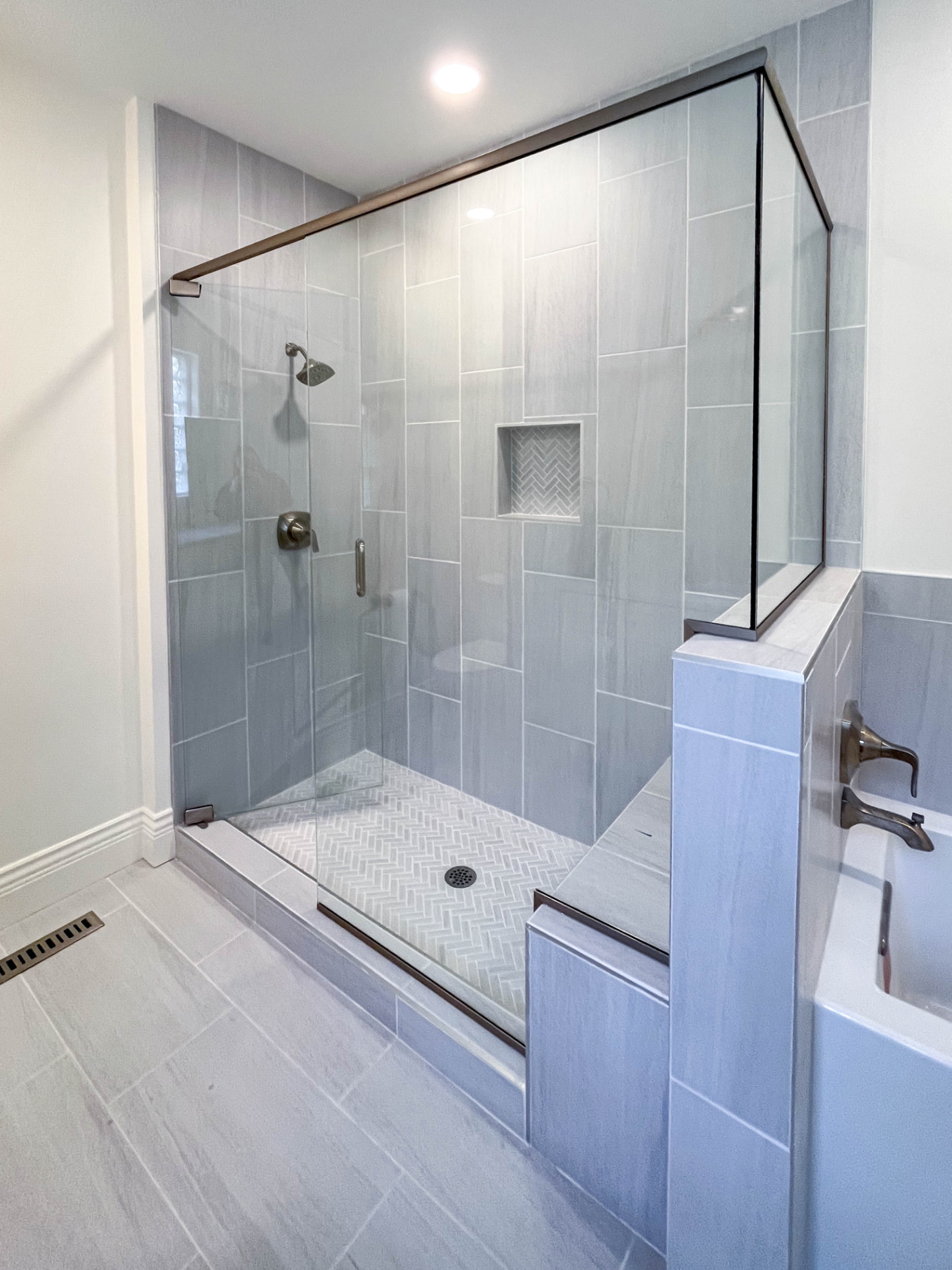 Remodeled bathroom with a glass-enclosed tiled shower and brass fixtures