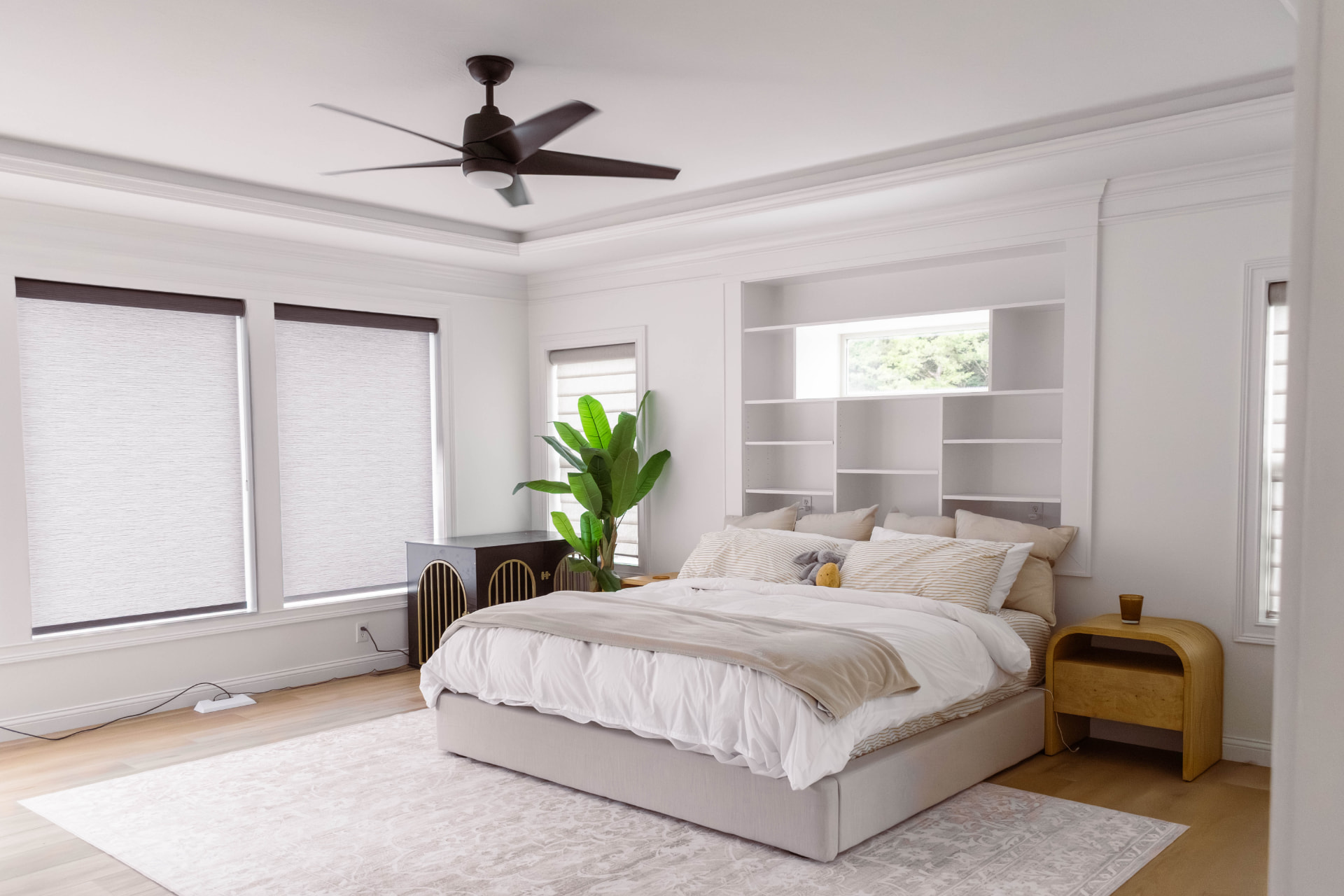 Remodeled primary bedroom with tray ceiling and built-in shelving