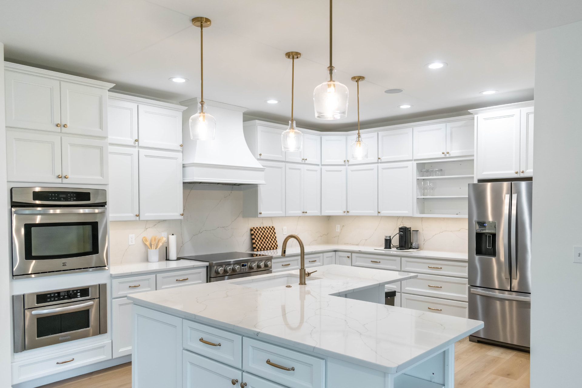 Remodeled kitchen with white cabinets, quartz counters and a stainless range