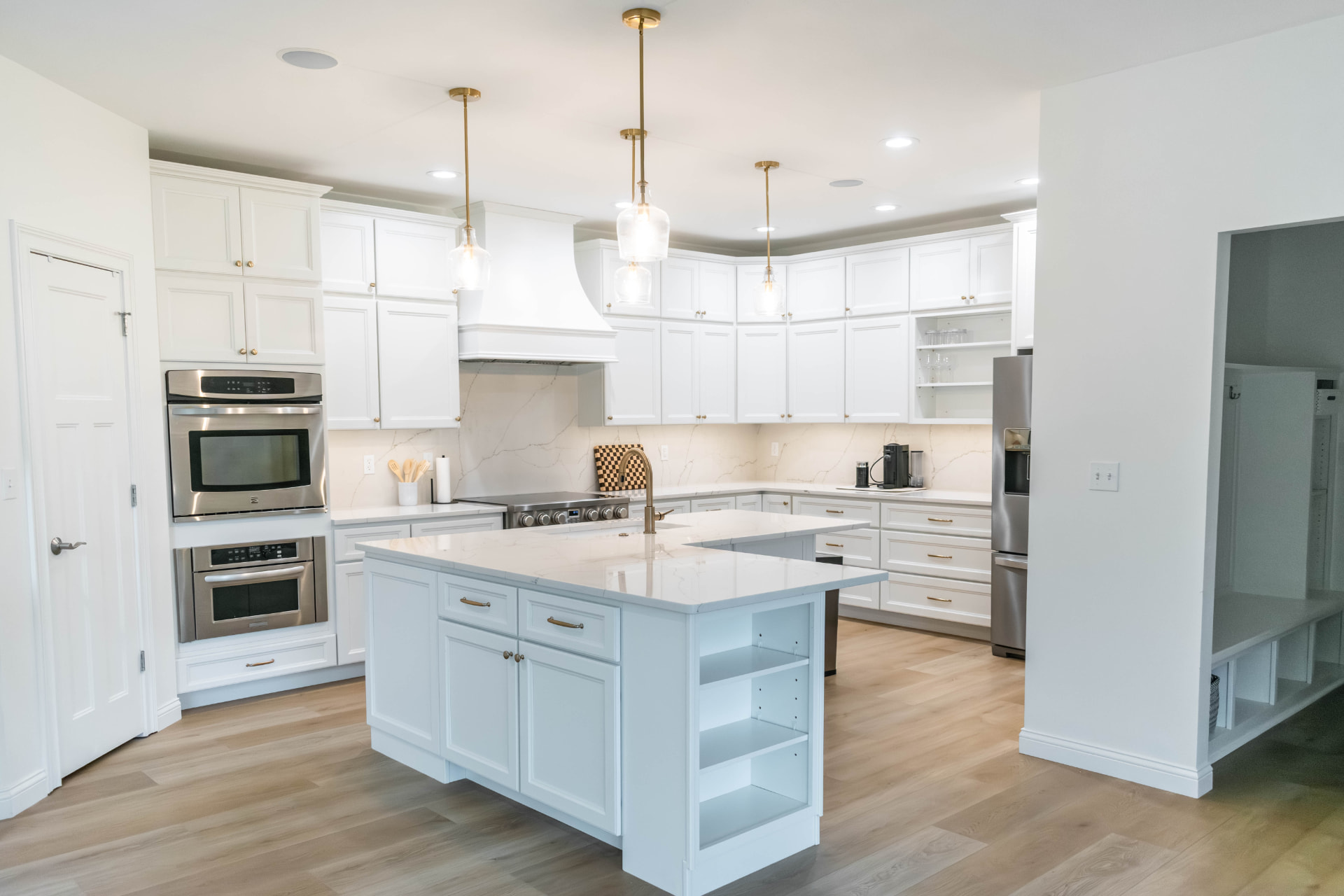 Remodeled white kitchen with quartz counters, a large island and pendant lighting