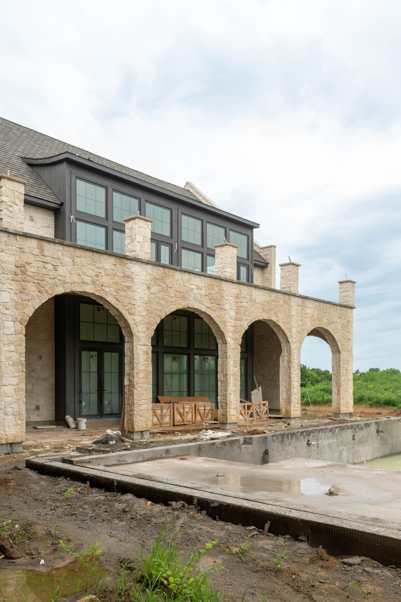Stone arched patio and rear elevation of a home under construction